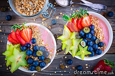Healthy breakfast bowl: raspberry smoothies with granola, blueberries, strawberries and carambola Stock Photo
