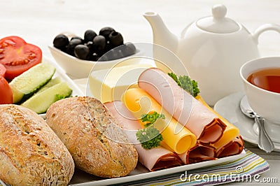 Healthy breakfast with cheese, ham, fresh bun, fresh vegetables, olives and tea. Stock Photo