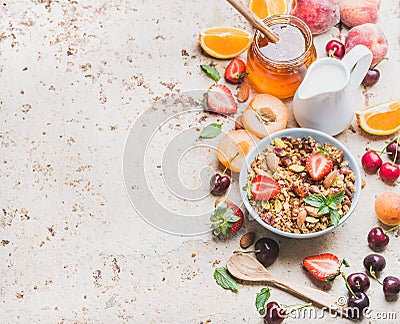 Healthy breakfast ingredients. Oat granola in bowl with nuts, strawberry and mint leaves, milk in pitcher, honey in Stock Photo