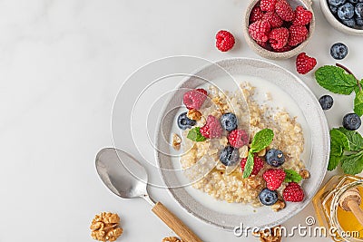 Healthy breakfast. Quinoa porridge with fresh berries, nuts and mint in a bowl with spoon on white background. top view Stock Photo