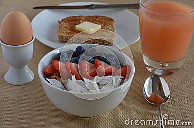 Healthy Breakfast Scene with grapefruite juice, boiled egg, sprouted grain toast, and steel cut oatmeal with fruit. Stock Photo