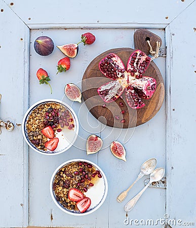Healthy breakfast set. Bowls of oat granola with yogurt, fresh strawberries, figs, pomegranate andd honey over light Stock Photo