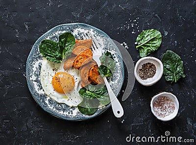 Healthy breakfast or snack - fried egg, baked sweet potato and spinach on dark background Stock Photo