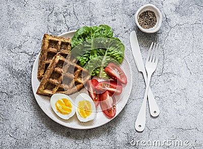 Healthy breakfast, snack - zucchini waffles, boiled egg, fresh tomatoes, lettuce on a gray background, top view Stock Photo