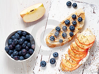 Healthy breakfast with sweet sandwiches - ricotta, blueberries, apple slices, peanut butter on white rustic wood table Stock Photo