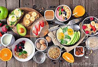 Healthy breakfast table scene with fruit, yogurts, oatmeal, smoothie, nutritious toasts and egg skillet, top view over wood Stock Photo