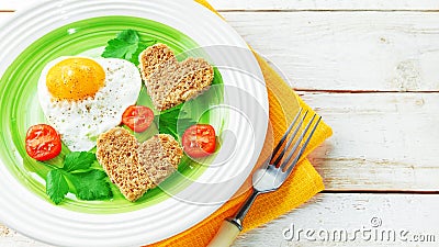 Healthy Breakfast on Valentine`s day fried eggs, bread heart-shaped and fresh tomatoes. Dietary food Stock Photo
