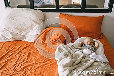 Healthy daytime sleep for the newborn. A child sleeps in the orthopedic Baby Cocoon on a larger bed in the parents room Stock Photo