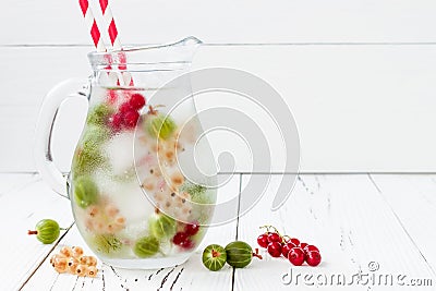 Healthy detox berry infused flavored water. Summer refreshing homemade drink with gooseberries and white and red currant on white Stock Photo