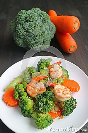 Healthy dish of prawn stir fried with broccoli and carrot served on white plate Stock Photo