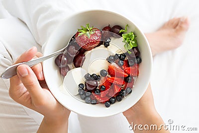 Healthy eating concept. Women`s hands holding bowl with cottage cheese with cream, strawberry, cherry, gooseberry and blueberry Stock Photo