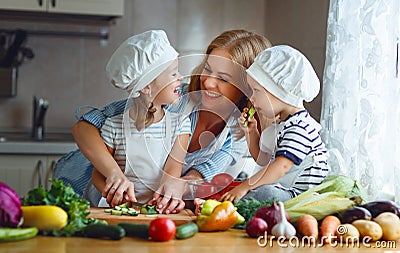 Healthy eating. Happy family mother and children prepares vegetable salad Stock Photo