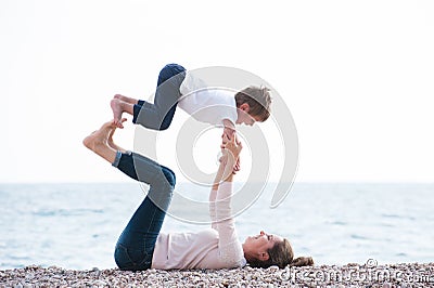 Healthy family playful pretty mother and child making exercises on autumn beach Stock Photo