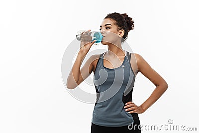 Healthy and Fitness concept - beautiful African American girl in sport clothes drinking water after workout. Isolated on Stock Photo