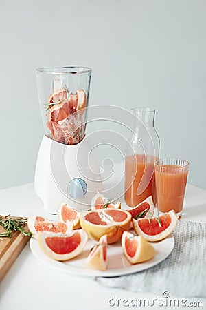 Healthy fitness diet breakfast over white wall. Grapefruit pieces and rosemary in blender. Detox refreshing smoothie. Stock Photo