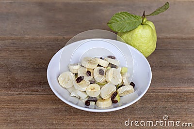 Healthy food banana slide guava block and raisins in white bowl on wood table. With copy space for text or design Stock Photo