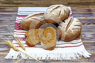 Healthy food concept. Three loaves of rye bread and pieces of sliced bread on a towel with Ukrainian national ornaments. Stock Photo