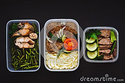 The healthy food in the containers on black background: snack, dinner, lunch. Baked fish, beans, beef cutlets, mashed potatoes, me Stock Photo