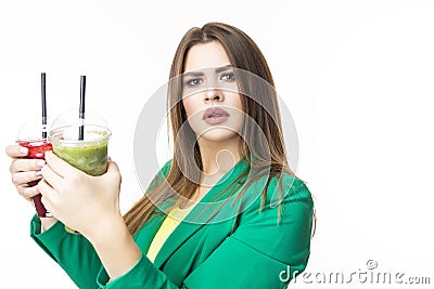 Healthy Food Eating. Choosy Thinking Woman With Both Green and Red Detox Vegetable Smoothie. Posing in Green Jacket Over White. Stock Photo