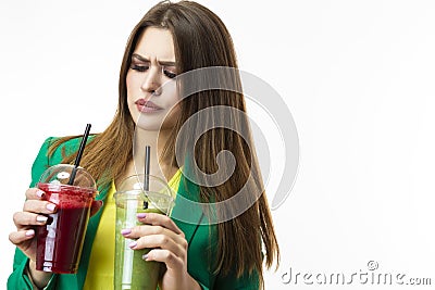 Healthy Food Eating. Woman Drinking Both Green and Red Detox Vegetable Smoothie. Posing in Green Jacket Over White. Stock Photo