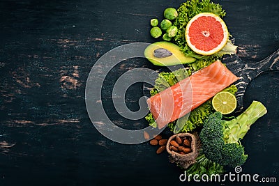 Healthy food. Fish salmon, avocado, broccoli, fresh vegetables, nuts and fruits. On a black background. Stock Photo