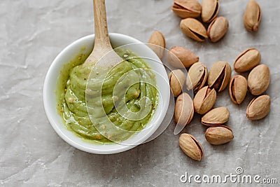 Healthy food, pistachio pasta and unpeeled salted pistachios, wooden spoon on a light background. Components for cooking Stock Photo