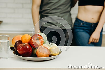 Fit couple snacking with fresh fruits at kitchen Stock Photo