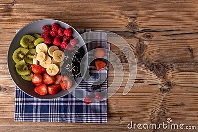 Healthy fruit salad in a greyblue plate on wood antique table and retro blue tablecloth Stock Photo