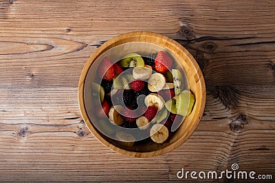 Healthy fruit salad in a wood plate on wood antique table and retro blu tablecloth Stock Photo