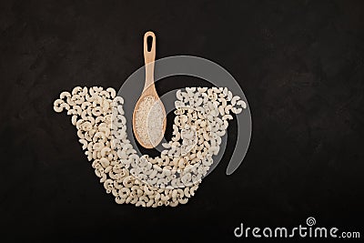 Healthy gluten-free pasta made from rice flour. Wooden spoon with rice. White pasta laid out in the shape of saucepan on dark Stock Photo