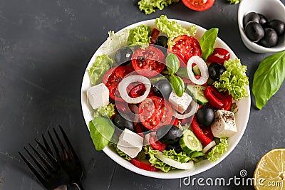 Healthy Greek salad of green lettuce, cherry tomato, onion, pepper, feta cheese, black olives, basil, cucumbers, with olive oil Stock Photo