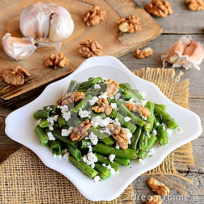 Healthy green beans salad with cottage cheese and walnuts on a white plate and a vintage wooden table. Rustic style Stock Photo