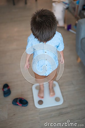 Healthy habits begin: Multiracial toddler weighing in at home Stock Photo