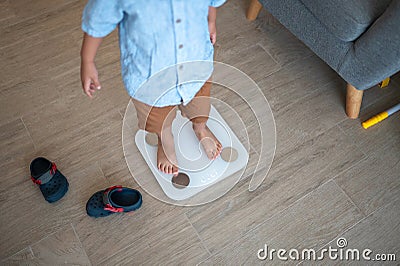 Healthy habits begin: Multiracial toddler weighing in at home Stock Photo