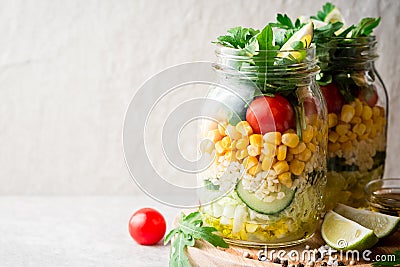 Healthy homemade salads with bulgur, vegetables and lime in mason jars on grey stone background. Stock Photo