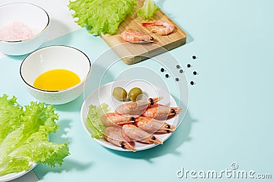 Healthy lifestyle - cooking of fresh salad of prawn, green salad, olive, black pepper, pink salt in sunlight with shadow, on white Stock Photo