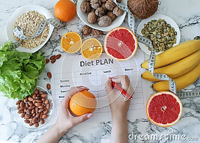 Young woman writing a diet plan. Fresh products set top view Editorial Stock Photo
