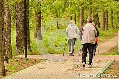 Healthy lifestyle. Nordic walking. Adult man and two women are engaged in athletic walking Editorial Stock Photo