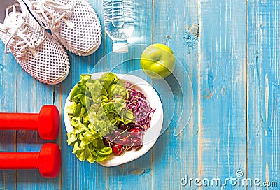 Healthy lifestyle sport equipment fitness, sneakers, green apple, fresh water and healthy food on blue wood background Stock Photo