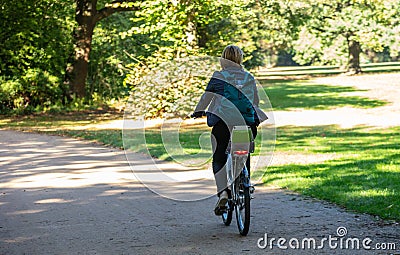 Healthy lifestyle. Woman is riding a bike in a path of Tiergarten park, Berlin, Germany. Nature background Editorial Stock Photo