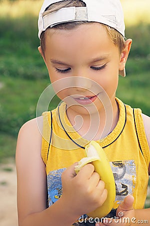 Healthy little boy eating banana. Happy kid enjoy eating fresh fruit. Stock Photo