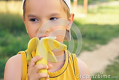 Healthy little boy eating bananaon nature background. Happy kid enjoy eating fresh fruit. Stock Photo