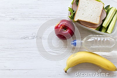 Healthy lunch box with sandwich, fruits and bottle of water on white wooden table, top view. From above, flat, overhead Stock Photo