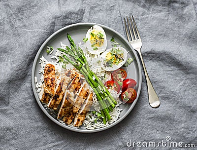 Healthy lunch - rice, asparagus, grilled chicken, boiled egg on a grey background, top view Stock Photo