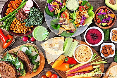 Healthy lunch table scene with nutritious Buddha bowl, lettuce wraps, vegetables, sandwiches and salad, above view over wood Stock Photo