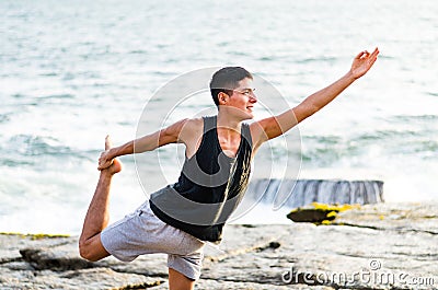 Healthy man practicing yoga. Stretching in natural position in Natarajasana, beautiful sea landscape, sunset, nature Stock Photo