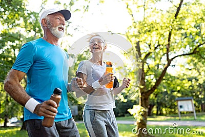 Healthy mature couple jogging in a park at early morning with sunrise Stock Photo