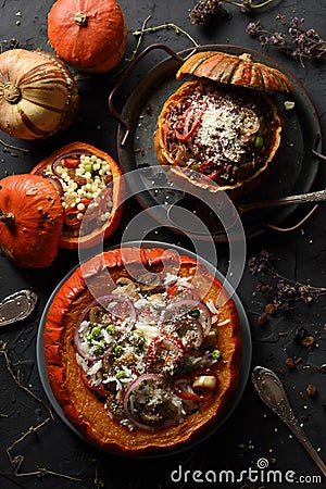 Healthy meat free food. Orange pumpkins stuffed with brown and white rice, giant couscous, mushrooms, onion and grated cheese on Stock Photo