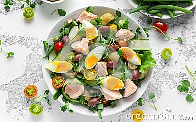 Healthy Nicoise salad with salmon, colourful sweet cherry tomatoes, olives, green beans, cucumber ribbons, soft boiled Stock Photo