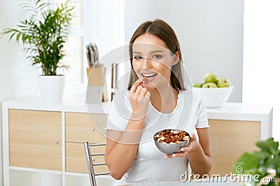 Healthy Nutrition. Beautiful Young Woman Eating Nuts Stock Photo